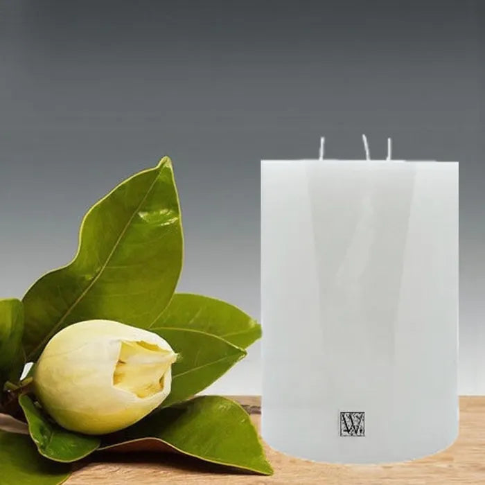 White candle with a floral arrangement on a wooden surface